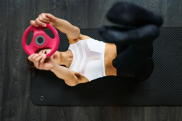 Young sportswoman on yoga mat doing situps in gym. — Stock Photo, Image