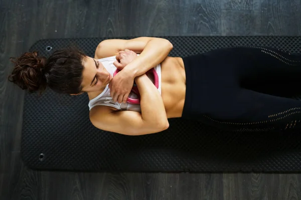 Young sportswoman on yoga mat doing situps in gym. — 스톡 사진