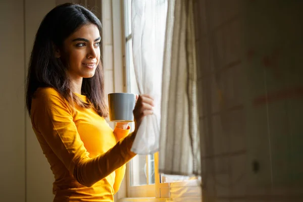 Persisk kvinna dricker kaffe medan du tittar genom fönstret — Stockfoto