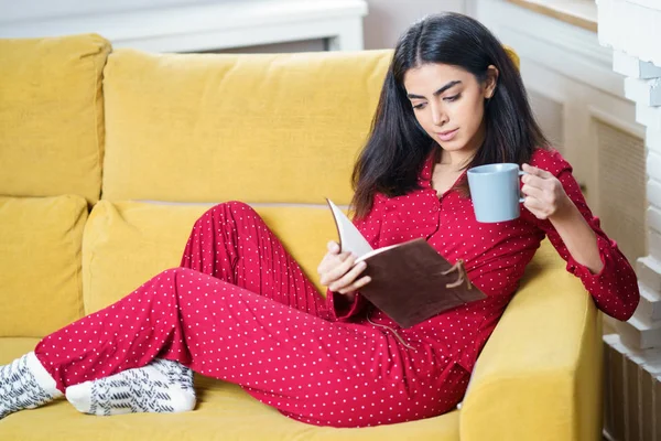 Evde çay içip kitap okuyan bir kadın var. — Stok fotoğraf