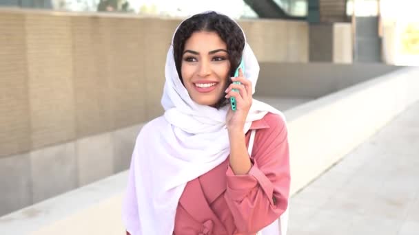 Νεαρή Μουσουλμάνα που φοράει μαντίλα χρησιμοποιώντας το smartphone της. — Αρχείο Βίντεο