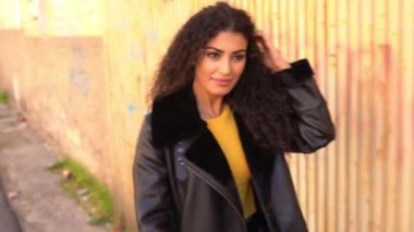 Genç Arap kadın dışarıda yürüyor, siyah kıvırcık saçlarını hareket ettiriyor.