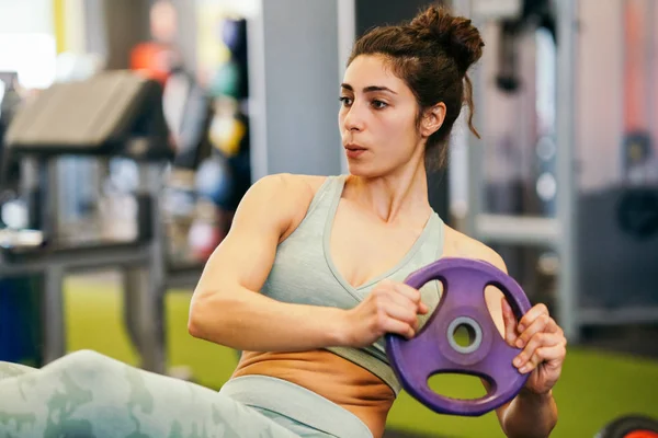 Jovem desportista no tapete de ioga fazendo situps no ginásio . — Fotografia de Stock