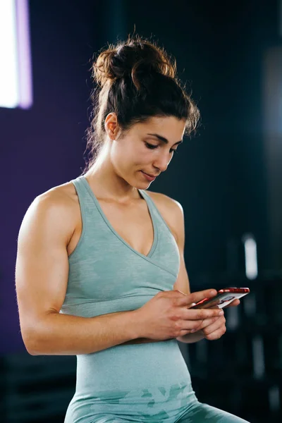 Frau beobachtet ihr Training auf ihrem Smartphone sitzend in einer Sprungbox — Stockfoto