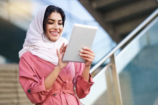 Mujer árabe joven usando hijab usando tableta digital al aire libre —  Fotos de Stock