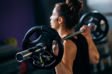 Spor salonundaki atletik kadın ağırlık kaldırıyor.