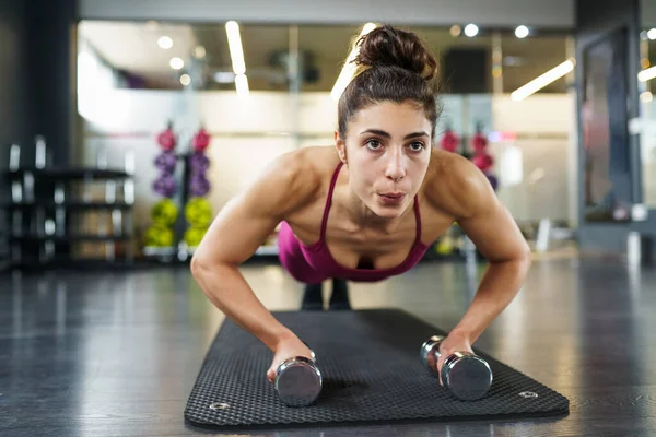 Mulher fazendo push-ups exercício com halteres em um treino de fitness — Fotografia de Stock