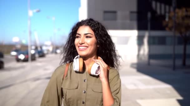 Mujer árabe joven caminando por la calle con auriculares — Vídeo de stock