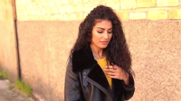 Молодая арабская женщина выходит на улицу, двигая своими черными кудрявыми волосами — стоковое видео