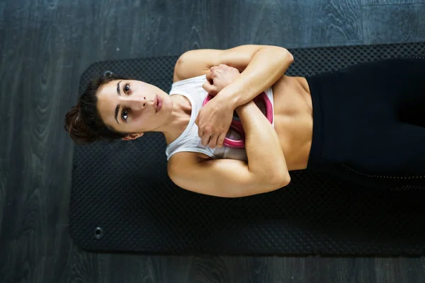 Young sportswoman on yoga mat doing situps in gym. — Stock Photo, Image