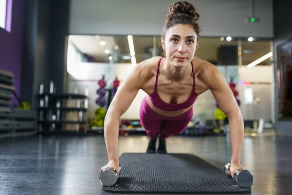 Woman doing push-ups exercise with dumbbell in a fitness workout — Stock Photo, Image
