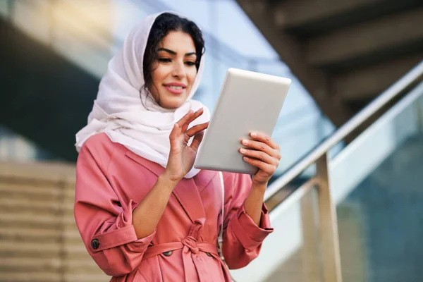 Mujer árabe joven usando hijab usando tableta digital al aire libre —  Fotos de Stock