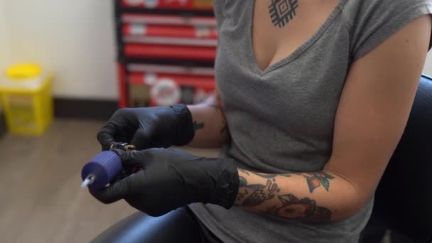 Vrouwelijke tatoeëerder opzetten van de tattoo machine. — Stockvideo