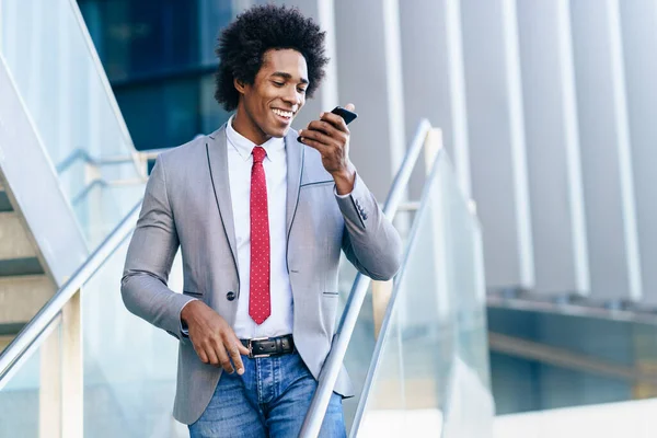 Black Businessman använder en smartphone nära en kontorsbyggnad — Stockfoto