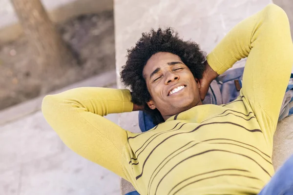 Černý turista s afro vlasy ležící na zemi venku. — Stock fotografie