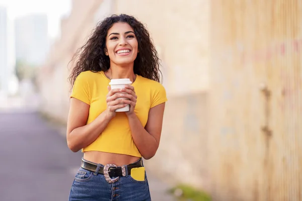 Arab girl walking across the street with a take-away coffee — Zdjęcie stockowe