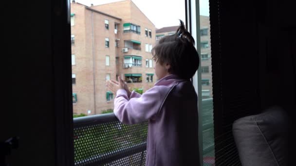 Chica aplaudiendo en la ventana en apoyo de las personas contra el coronavirus — Vídeos de Stock