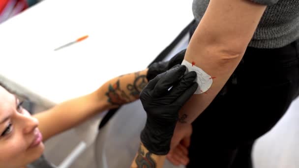 Mujer tatuadora poniendo el diseño en el brazo shes va a tatuaje . — Vídeos de Stock