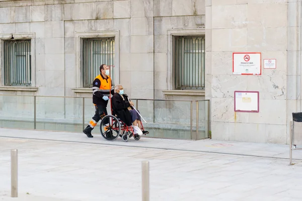 GRANADA HISZPANIA 23 KWIECIEŃ 2020. Sanitariusz zabiera starszą kobietę na wózku inwalidzkim do szpitala — Zdjęcie stockowe