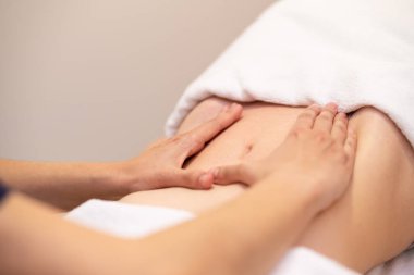 Kadın spa salonunda karın masajı yaptırıyor.