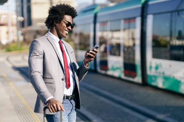Hombre de negocios negro sonriente esperando el próximo tren —  Fotos de Stock