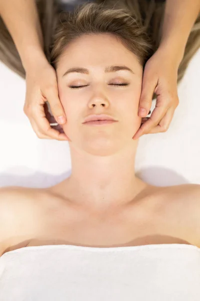 Jovem loira recebendo uma massagem na cabeça em um centro de spa . — Fotografia de Stock