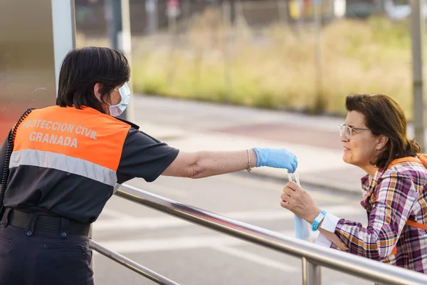 Жінка з цивільного захисту роздає маски для захисту від Ковід-19 — стокове фото