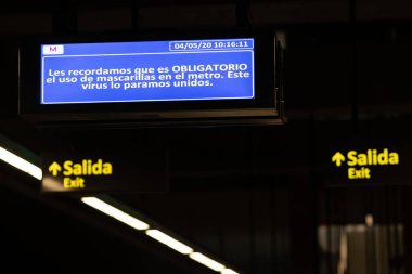 Büyükbaba, İspanya 'ya. 4 Mayıs 2020. Trende maske kullanmanın zorunlu olduğunu belirten bir tren istasyonundaki aydınlatma işareti..