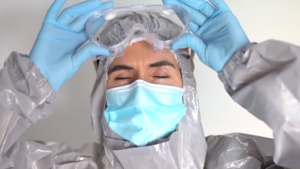 Médico em Equipamento de Proteção Pessoal colocando os óculos de segurança — Vídeo de Stock