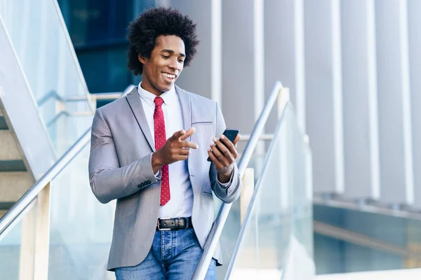 Black Businessman använder en smartphone nära en kontorsbyggnad — Stockfoto