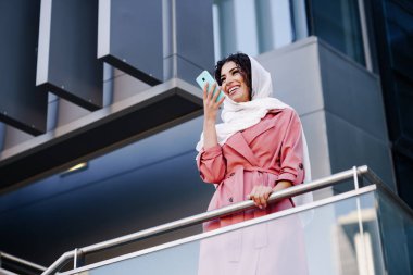 Türbanlı Müslüman Kadın akıllı telefonuyla ses kaydı yapıyor.