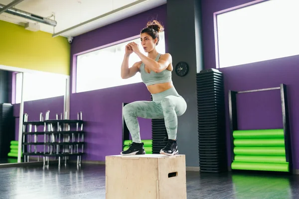 Spor salonundaki kadın egzersiz rutininin bir parçası olarak kutuya atlıyor.. — Stok fotoğraf