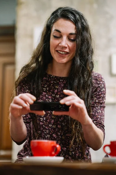 Mujer joven con un poco de pelo gris usando un teléfono inteligente en un café . — Foto de Stock