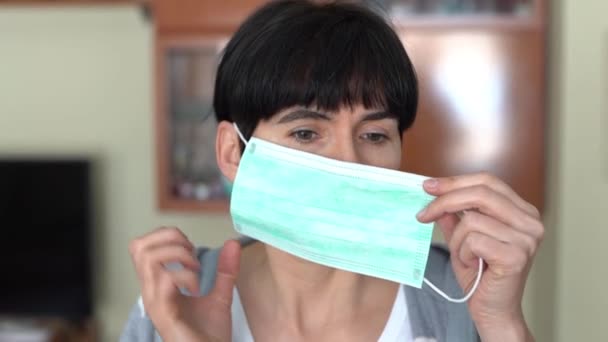 Woman putting on a medical mask at home as protection against the coronavirus. — Stock Video