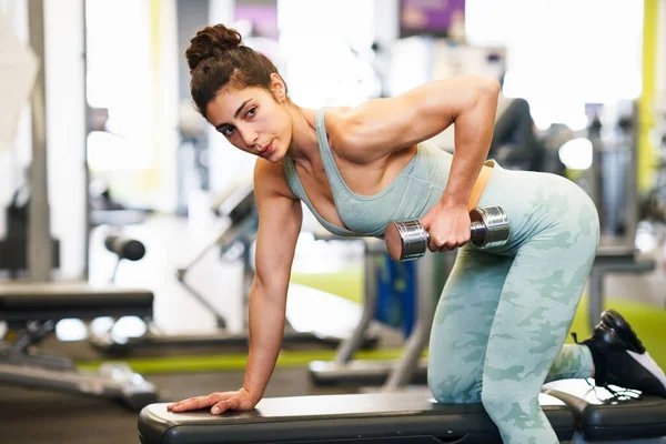 Vrouw werkt aan haar triceps en biceps in een sportschool met halters — Stockfoto