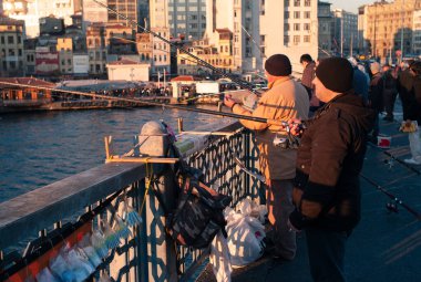 Istanbul, Turkey - January 3 2012: Local Fishermen Angling on the Galata Bridge at the Golden Horn with Fishing Rods on the Railing