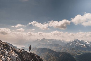 distant view of hiker standing on cliff of mountain at sunny day
