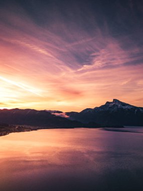 Avustralya 'da bir göldeki iskelede gün doğumu ve dağların manzarası.