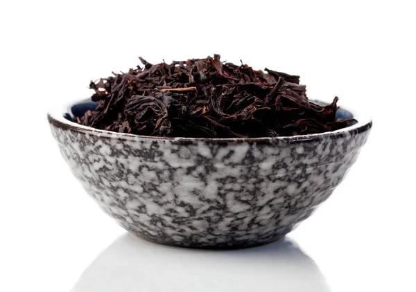 Svart te blad i en kopp på en vit bakgrund — Stockfoto