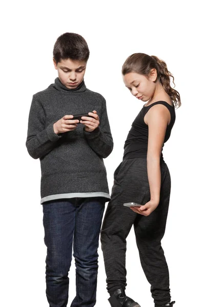 Teini-ikäinen poika ja tyttö älypuhelimellaan — kuvapankkivalokuva