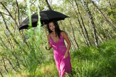 Siyah şemsiye ile ormanda yürüyen kadın