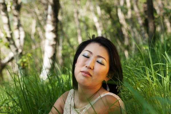 Азиатский портрет женщины, сидящей на траве — стоковое фото