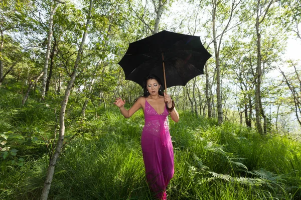 Mujer caminando en el bosque con paraguas negro — Foto de Stock