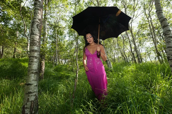 Mujer caminando en el bosque con paraguas negro — Foto de Stock