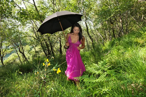 Frau spaziert mit schwarzem Regenschirm im Wald — Stockfoto