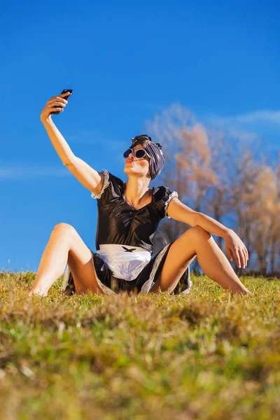 Slutet städhjälp sitter i gräset med telefonen — Stockfoto