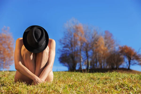 Nacktes Mädchen, das mit überkreuzten Beinen auf dem Gras sitzt, Konzept — Stockfoto