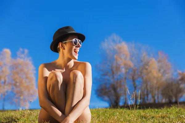 Nacktes Mädchen, das mit überkreuzten Beinen auf dem Gras sitzt, Konzept — Stockfoto