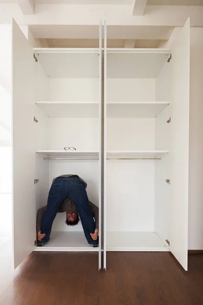 Człowiek w szafie robi ćwiczenia, koncepcja — Zdjęcie stockowe