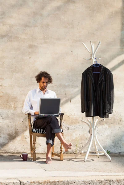 Portrait of a young man on a wall, with laptop — Stock Photo, Image